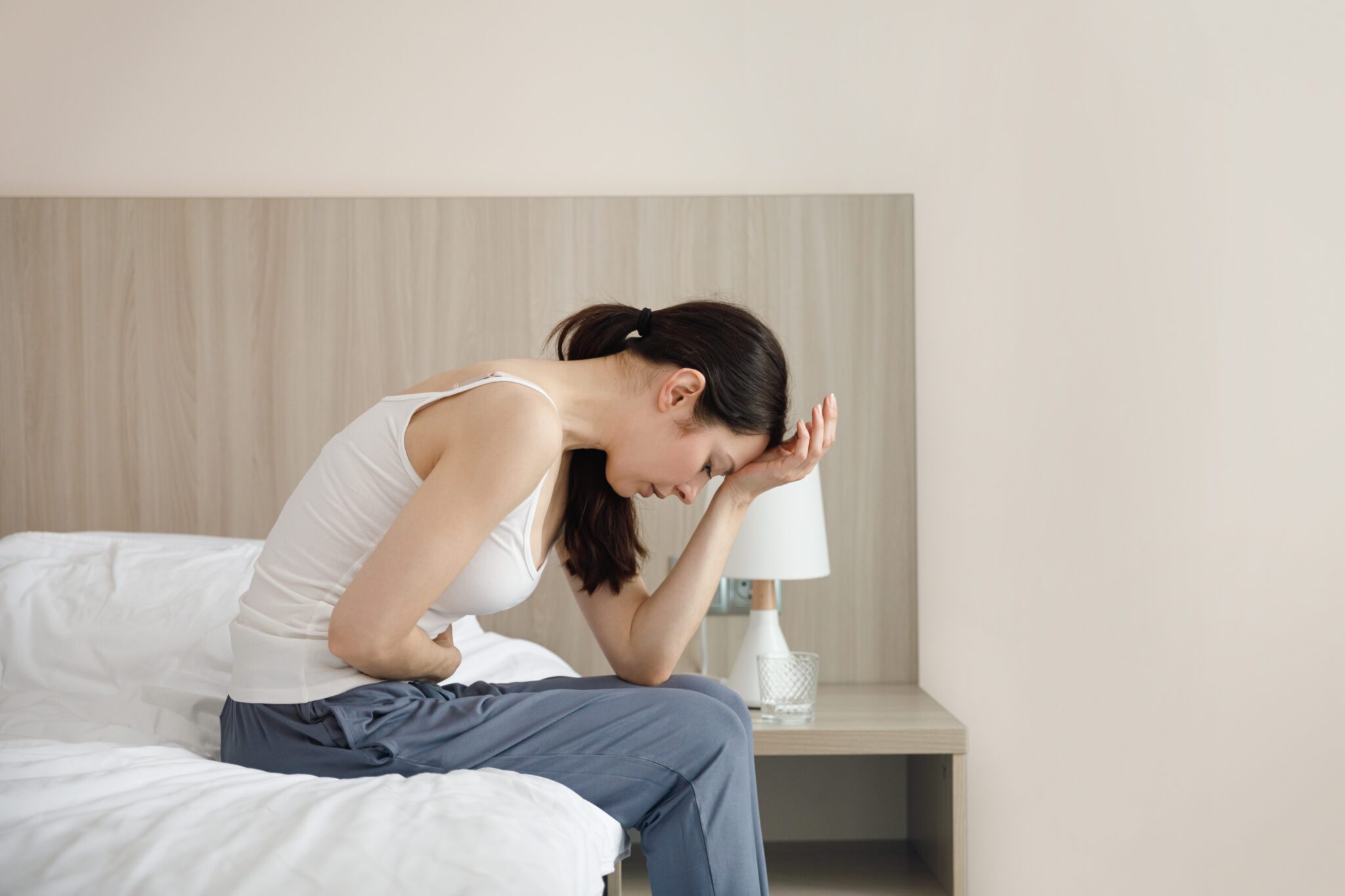 Woman in pain sitting on bed